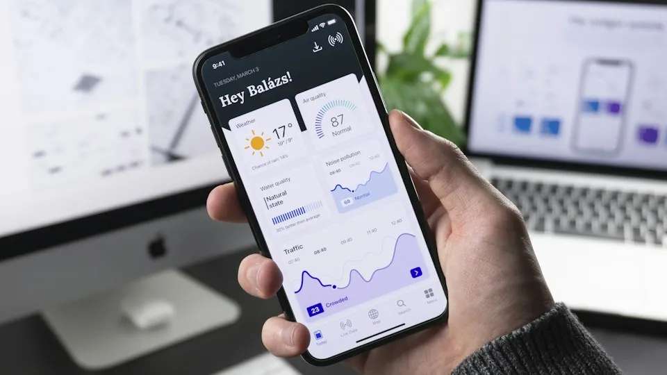 Hand holding a smartphone showing a mobile app dashboard