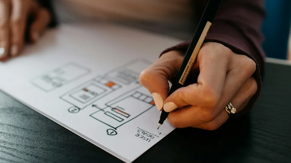 Designer sketching website and mobile app wireframes on paper